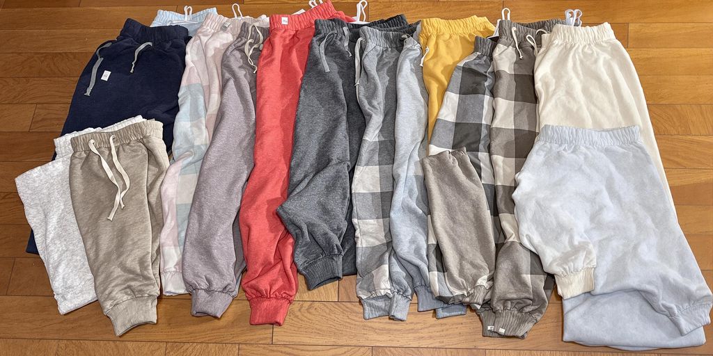 Variety of colorful sweatpants displayed on a wooden floor.